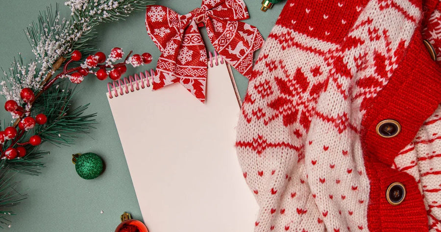 Red Christmas sweater and blank notebook arranged for family photo outfit planning